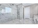 Modern glass shower with marble-tiled walls complemented by marble floors, natural light, and sleek fixtures at 33759 Ocean Spray Ln, Wesley Chapel, FL 33543