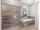 Luxurious bathroom featuring a glass enclosed shower and a soaking tub with a window view at 344A Bay St, Palm Harbor, FL 34683