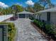 Paver driveway with lush landscaping leading to a gray garage and a red convertible car at 524 Park S St, St Petersburg, FL 33707