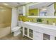 Bright bathroom features a double sink vanity, framed mirror, toilet, and shower with a shower curtain at 6181 Bahia Del Mar Blvd # 112, St Petersburg, FL 33715