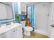 A well-lit full bathroom with a shower, vanity, toilet, and colorful surf-themed shower curtain at 6181 Bahia Del Mar Blvd # 112, St Petersburg, FL 33715