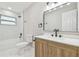 Modern bathroom featuring a wood vanity, white marble-style tile, and dark fixtures at 7013 24Th S Ave, Tampa, FL 33619