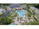 Aerial view of a large community pool with lounge chairs, mature landscaping, and nearby clubhouse at 10205 Courtney Palms Blvd # 304, Tampa, FL 33619