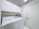 Bright laundry room with white appliances and overhead storage cabinets at 1042 Trafalgar Dr, New Port Richey, FL 34655