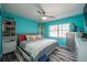 Bedroom featuring vibrant blue walls, ceiling fan, gray and white furniture, and large window at 12005 Wren Ct, New Port Richey, FL 34654