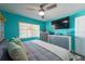 Bedroom featuring vibrant blue walls, ceiling fan, gray and white furniture, and large window at 12005 Wren Ct, New Port Richey, FL 34654