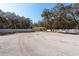 A home with a two-car garage surrounded by mature trees, a well-kept lawn, and a white fence at 12005 Wren Ct, New Port Richey, FL 34654