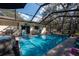 Screened pool area with an in-ground pool and hot tub with patio furniture on the deck and an enclosed screen at 12005 Wren Ct, New Port Richey, FL 34654