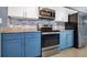 Close up of the kitchen features stainless steel oven, microwave, and blue colored cabinets at 1316 W Hiawatha St, Tampa, FL 33604