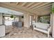 Covered patio with tile floor, seating, TV and view of tropical landscaping and swimming pool at 17404 1St E St, Redington Shores, FL 33708