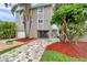 Exterior of a two-story home featuring gray siding, a brick driveway, and lush tropical landscaping at 17404 1St E St, Redington Shores, FL 33708