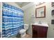 Bathroom featuring blue-and-white shower curtain, cherry vanity, white sink, a wood-framed mirror and tiled floor at 1751 8Th Sw Ave, Largo, FL 33770