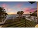 Waterfront backyard featuring a dock, boat lift, fenced yard, and tropical sunset at 1843 Bayou Grande Ne Blvd, St Petersburg, FL 33703