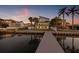 Rear exterior view of home with lawn, dock, fence, balconies, and tropical landscaping at dusk at 1843 Bayou Grande Ne Blvd, St Petersburg, FL 33703