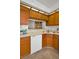 Functional kitchen with wooden cabinetry, white appliances, and a pass-through window at 2446 Bentley Dr, Palm Harbor, FL 34684