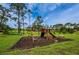 Community playground featuring a swing set, slide, climbing structure, and benches in a grassy area at 2446 Bentley Dr, Palm Harbor, FL 34684