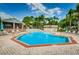 Community swimming pool with lounge chairs and umbrellas beside a poolside building and mature trees at 2446 Bentley Dr, Palm Harbor, FL 34684