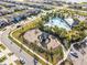 Community aerial view featuring a playground, pool, and manicured landscaping amid modern homes and tranquil lakes at 3148 Marine Grass Dr, Wimauma, FL 33598