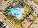 Aerial view of a clover-shaped community pool surrounded by lush landscaping, seating, and ample parking at 3148 Marine Grass Dr, Wimauma, FL 33598