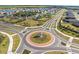 Aerial view of a roundabout amidst a planned community, featuring modern homes and scenic lakes at 3148 Marine Grass Dr, Wimauma, FL 33598