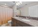Bright bathroom featuring dual sinks with granite countertops and a shower with patterned curtain at 3148 Marine Grass Dr, Wimauma, FL 33598