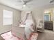 Charming bedroom with pink accents, featuring a canopy bed, soft lighting, and an en-suite bathroom for added convenience at 3148 Marine Grass Dr, Wimauma, FL 33598