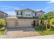 Two-story home featuring a three-car garage, brick accents, and a well-manicured lawn at 3148 Marine Grass Dr, Wimauma, FL 33598