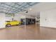 Spacious garage featuring epoxy floors, custom cabinets, workbenches, and a yellow convertible at 3148 Marine Grass Dr, Wimauma, FL 33598