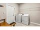 Well-lit laundry room with modern washer and dryer, storage shelf, and tile flooring at 3148 Marine Grass Dr, Wimauma, FL 33598