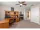 A home office with wood furnishings, a ceiling fan, and carpeted floors, creating a functional and comfortable workspace at 3148 Marine Grass Dr, Wimauma, FL 33598