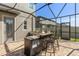 A built-in outdoor kitchen features a grill, prep area, and bar seating on the patio at 3148 Marine Grass Dr, Wimauma, FL 33598