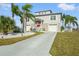 Charming two-story home featuring a red front door, lush landscaping, and a paved driveway at 3415 Croaker Dr, Hernando Beach, FL 34607