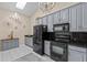 Well-lit kitchen featuring modern black appliances, granite countertops, stylish cabinetry, and tile flooring at 39650 Us Highway 19 N # 244, Tarpon Springs, FL 34689