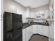 Bright kitchen with white cabinets, subway tile backsplash, black appliances, and gray plank flooring at 400 5Th S Ave, Safety Harbor, FL 34695