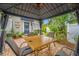 Covered patio area with a dining table, lush greenery, and a view of the home's charming entrance at 400 5Th S Ave, Safety Harbor, FL 34695