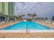 Outdoor pool with many lounge chairs, umbrellas, and views of the building and some palm trees at 400 64Th Ave # 1108, St Pete Beach, FL 33706