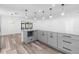 Open kitchen featuring gray cabinets, an island, modern lighting, and an adjacent living area at 4390 6Th Isle Dr, Hernando Beach, FL 34607