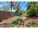 Large backyard surrounded with a wooden fence and lush green trees, plants, and grass at 5101 Estates Cir, Sarasota, FL 34243