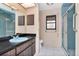 Tiled bathroom featuring a vanity with ample storage and a walk-in shower with glass door at 5101 Estates Cir, Sarasota, FL 34243