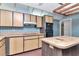 Retro kitchen with wood cabinets, brick flooring, an island, and plaid wallpaper at 5101 Estates Cir, Sarasota, FL 34243