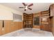 Room featuring a wood paneled wall, ceiling fan, and built in shelving at 5101 Estates Cir, Sarasota, FL 34243