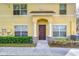 Welcoming entrance to this yellow townhome featuring stone accents and an arched entryway with a dark wood door at 6262 Timberly Ln # 99, Zephyrhills, FL 33542