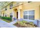 Townhouse exterior featuring a covered entrance, well-manicured landscaping, and a bright yellow facade at 6262 Timberly Ln # 99, Zephyrhills, FL 33542