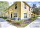 Corner view of yellow townhouses with stone-accented columns, tidy landscaping, and visible unit numbers at 6262 Timberly Ln # 99, Zephyrhills, FL 33542