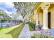 Exterior view of a yellow townhouse near a pool, featuring a sidewalk, landscaping, and a visible unit number at 6262 Timberly Ln # 99, Zephyrhills, FL 33542
