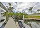 View of boat dock with boat lift and surrounding greenery, on a sunny, partly cloudy day at 6467 Rubia Cir, Apollo Beach, FL 33572