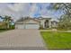 Charming home showcasing a 3-car garage, paved driveway, manicured lawn, and lush landscaping at 6467 Rubia Cir, Apollo Beach, FL 33572