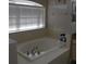 Large soaking tub with chrome fixtures under a bright window, next to a granite topped vanity at 6513 Sand Shore Ln, New Port Richey, FL 34652
