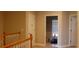 Upstairs hallway with wood railing, neutral colored walls, multiple doors, and a window at end at 6513 Sand Shore Ln, New Port Richey, FL 34652