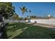 Beautiful backyard view with a white fence, lush green lawn, palm tree and blue house at 7 Georgia Ave, Crystal Beach, FL 34681